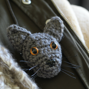 A personalised crocheted brooch with the face of your cat, created from your photographs and lovingly attached to a secure closing brooch pin.