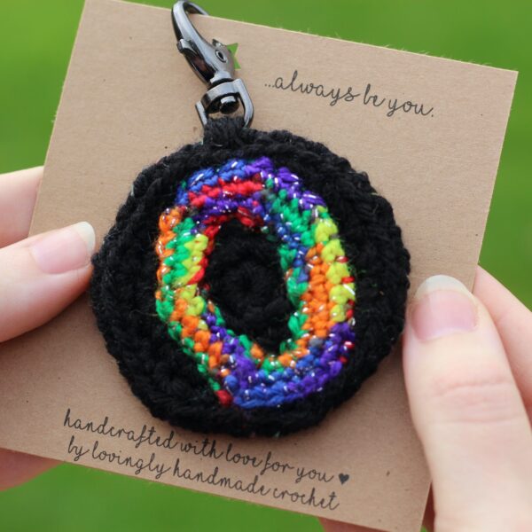 A personalised statement keyring featuring a rainbow letter of your choice set on a black background with a muted colour palette rainbow reverse.