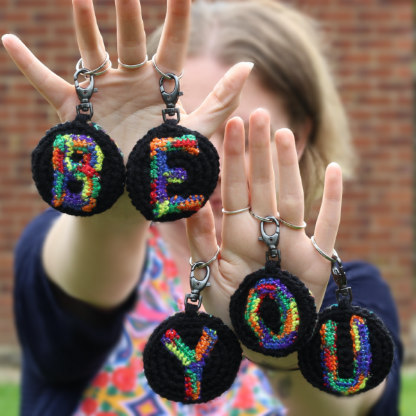 A personalised statement keyring featuring a rainbow letter of your choice set on a black background with a muted colour palette rainbow reverse.