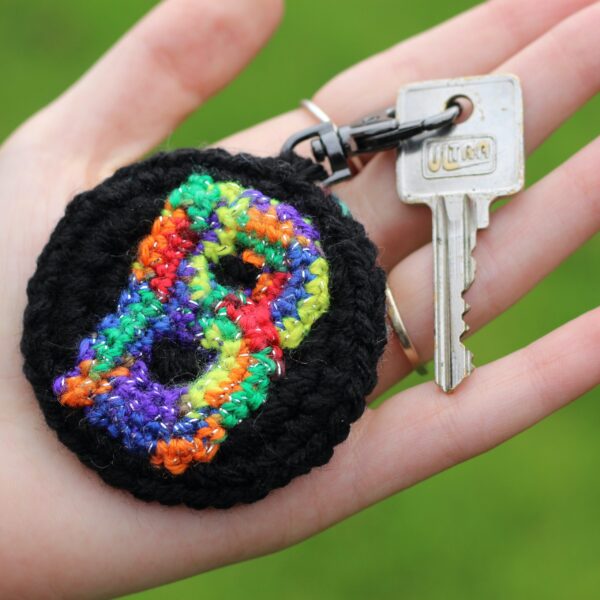 A personalised statement keyring featuring a rainbow letter of your choice set on a black background with a muted colour palette rainbow reverse.