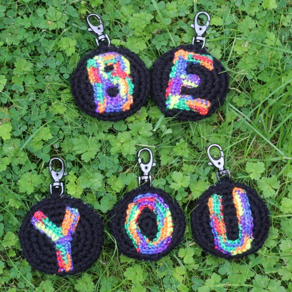 A personalised statement keyring featuring a rainbow letter of your choice set on a black background with a muted colour palette rainbow reverse.