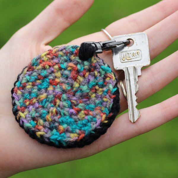 A personalised statement keyring featuring a rainbow letter of your choice set on a black background with a muted colour palette rainbow reverse.