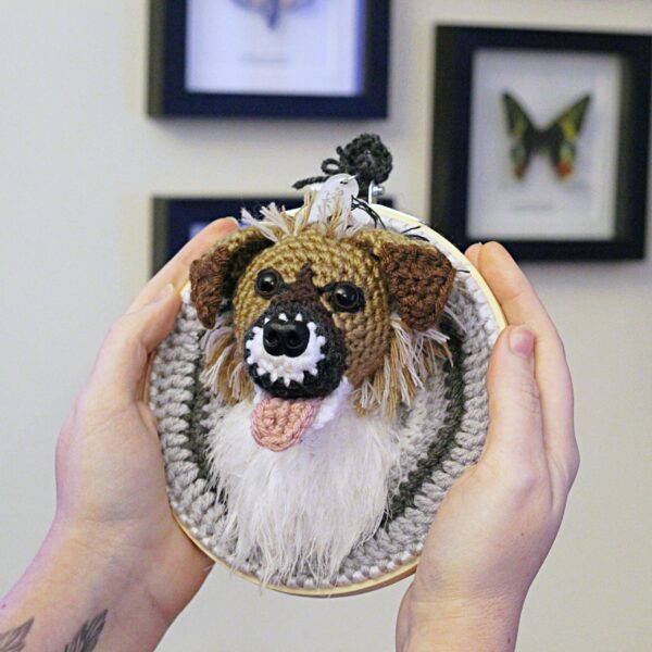 A bespoke and handcrafted crochet soft toy head created from photographs of your furry companion, lovingly mounted on a hanging embroidery hoop.