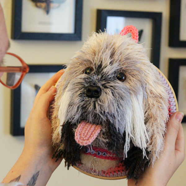 A bespoke and handcrafted crochet soft toy head created from photographs of your furry companion, lovingly mounted on a hanging embroidery hoop.