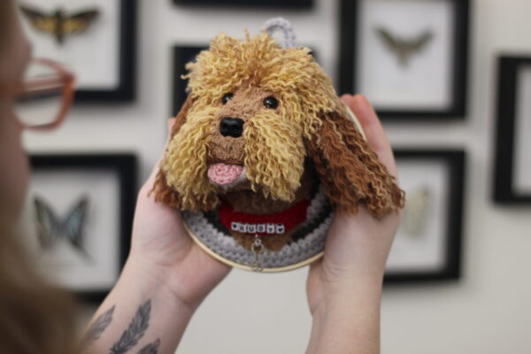 A bespoke and handcrafted crochet soft toy head created from photographs of your furry companion, lovingly mounted on a hanging embroidery hoop.