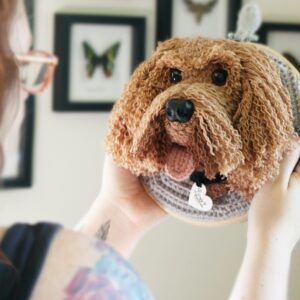 A bespoke and handcrafted crochet soft toy head created from photographs of your furry companion, lovingly mounted on a hanging embroidery hoop.